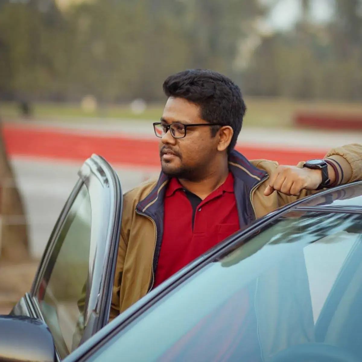 J S Mahboob standing beside a car with its door open